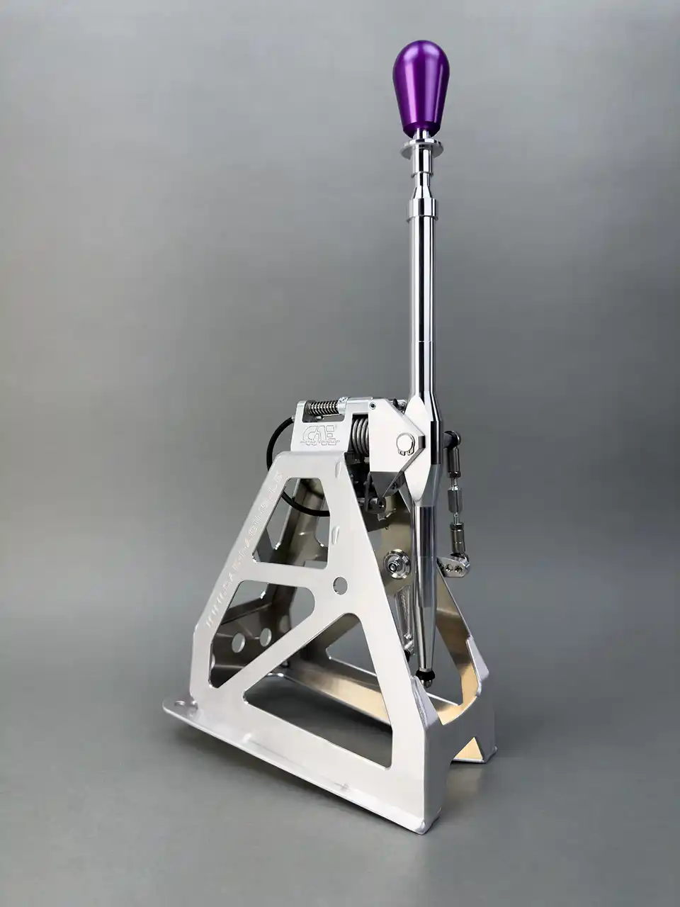 Studioaufnahme eines CAE Ultra Shifters aus silberfarbenem Aluminium mit violettem Schaltknauf für den Ford Fiesta 01-08 auf grauem Hintergrund